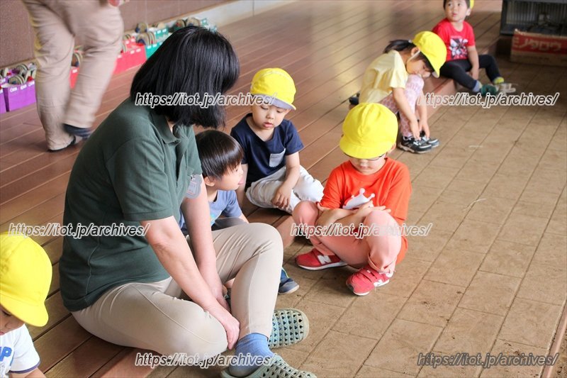 縁側にすわる園長先生と子どもたち