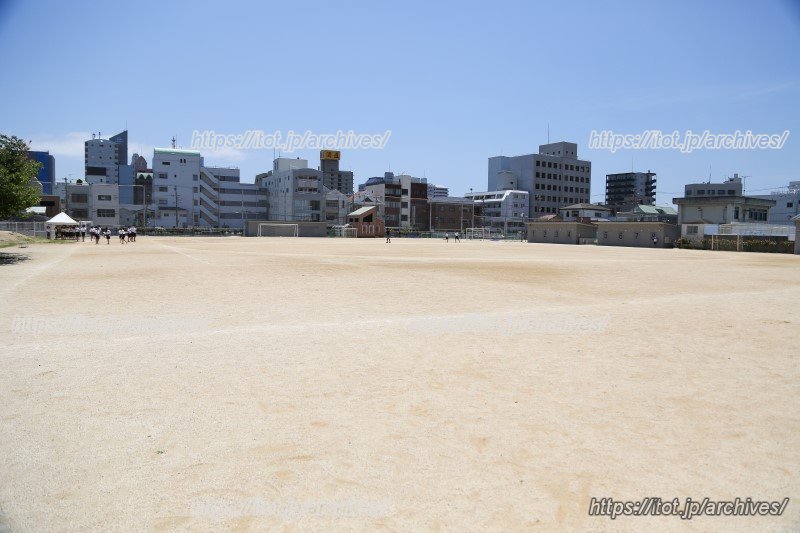 広い運動場。奥にはテニスコート、プール、学校菜園がある。