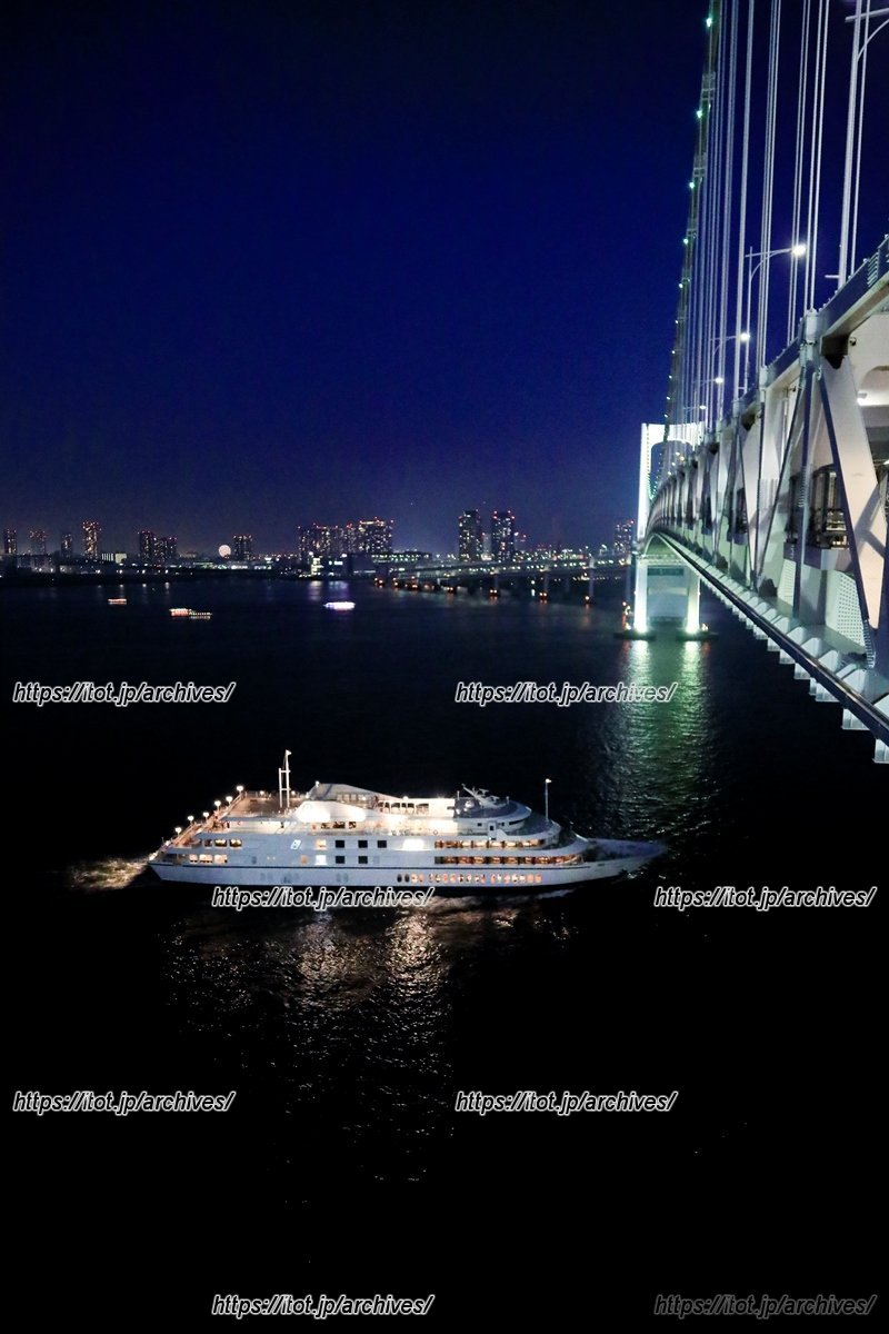 夜のレインボーブリッジを通過するクルーズ船