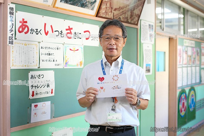 「あいさつチャレンジ表」を持つ、井上校長先生