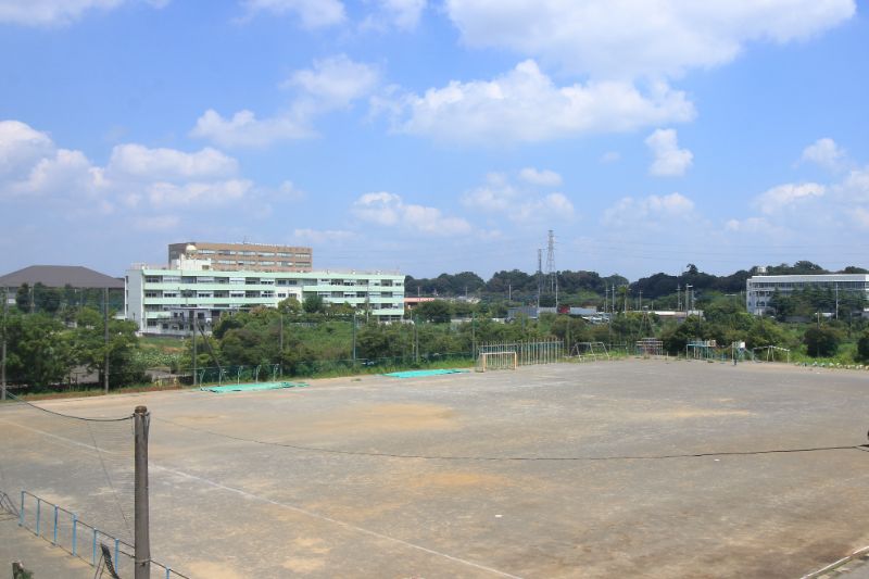 校庭の向こうには、「在家中学校」と後ろに建つ「埼玉学園大学」が見える